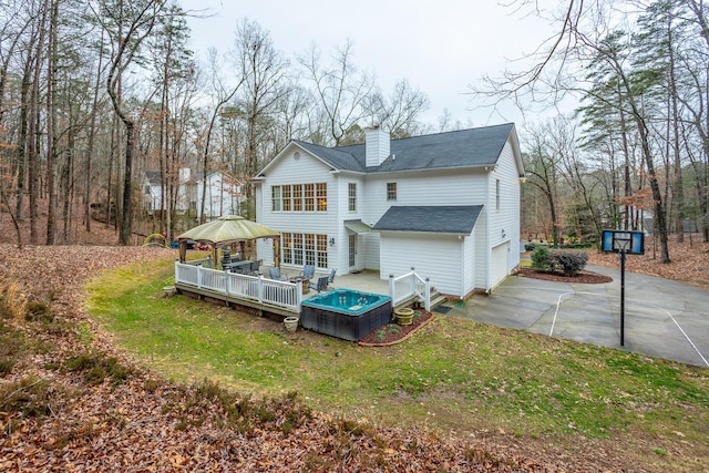 back of property with a wooden deck, a garage, and a lawn