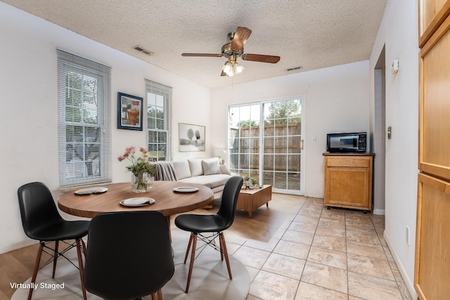 dining area featuring ceiling fan and a textured ceiling