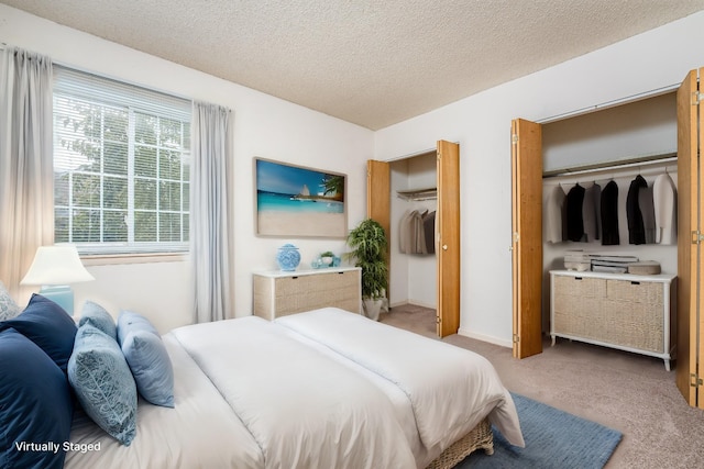 bedroom featuring carpet floors, two closets, and a textured ceiling