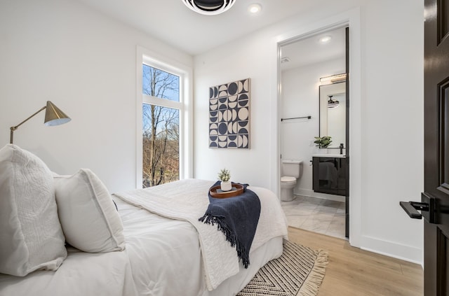 bedroom with connected bathroom and light hardwood / wood-style floors