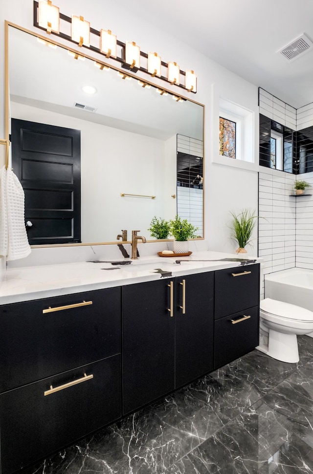 bathroom featuring vanity, a washtub, and toilet