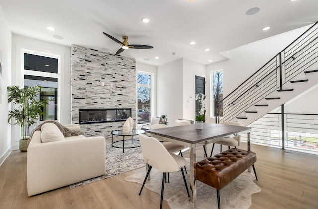 dining area featuring a tiled fireplace, light hardwood / wood-style floors, and ceiling fan