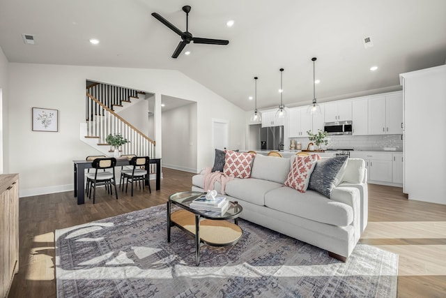 living room with hardwood / wood-style floors, vaulted ceiling, and ceiling fan