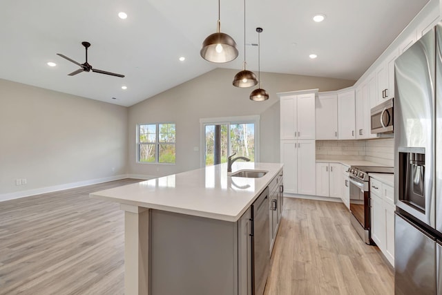 kitchen featuring sink, a center island with sink, appliances with stainless steel finishes, pendant lighting, and white cabinets