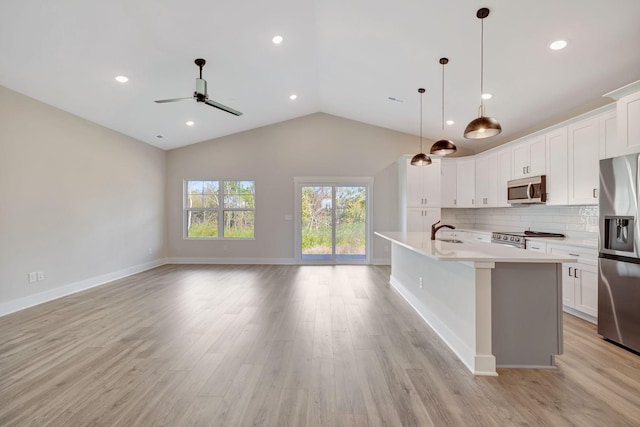 kitchen with sink, white cabinetry, pendant lighting, stainless steel appliances, and a kitchen island with sink