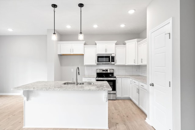 kitchen featuring sink, stainless steel appliances, an island with sink, and white cabinets