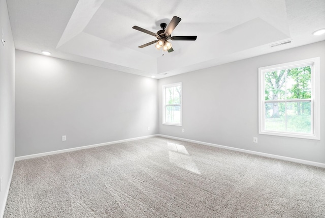 unfurnished room featuring ceiling fan, carpet flooring, and a raised ceiling