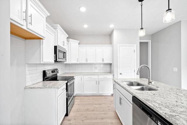 kitchen with pendant lighting, sink, white cabinets, and appliances with stainless steel finishes