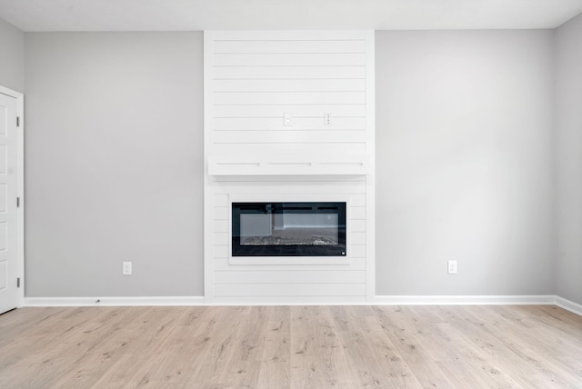 interior space featuring wood-type flooring and a large fireplace