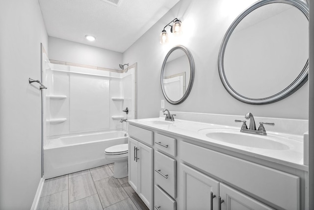 full bathroom with shower / washtub combination, vanity, a textured ceiling, and toilet