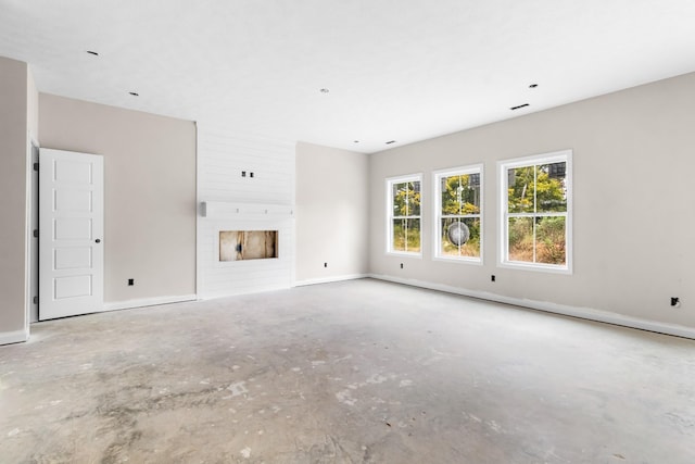 unfurnished living room with a fireplace and concrete flooring