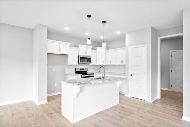 kitchen with appliances with stainless steel finishes, sink, a center island with sink, and white cabinets