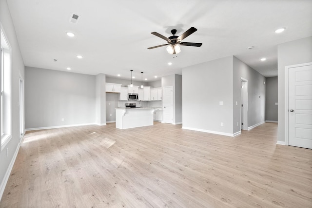 unfurnished living room featuring ceiling fan and light hardwood / wood-style flooring