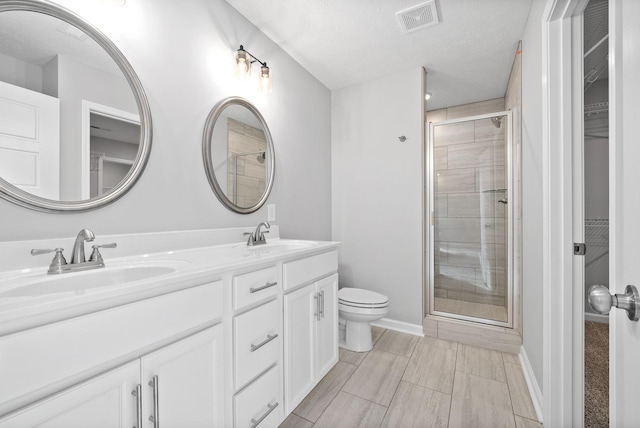 bathroom with vanity, a textured ceiling, toilet, and walk in shower