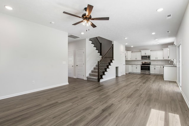 unfurnished living room featuring ceiling fan, sink, and dark hardwood / wood-style flooring