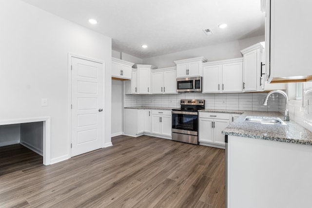 kitchen with sink, light stone counters, dark hardwood / wood-style floors, stainless steel appliances, and white cabinets