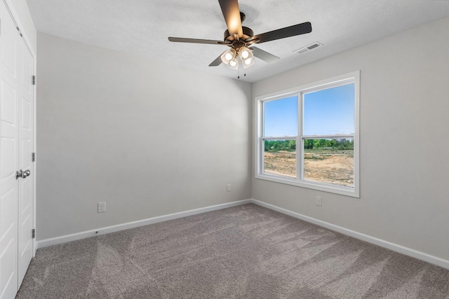 carpeted empty room featuring ceiling fan and a textured ceiling