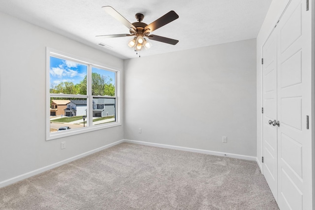 carpeted spare room with a textured ceiling and ceiling fan