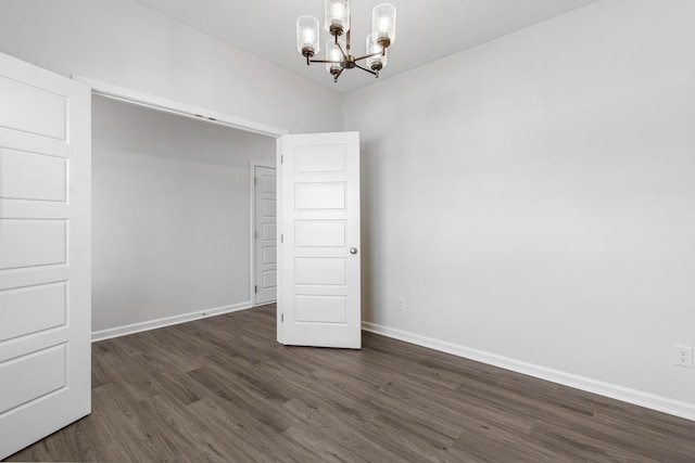 spare room featuring dark hardwood / wood-style flooring and a notable chandelier