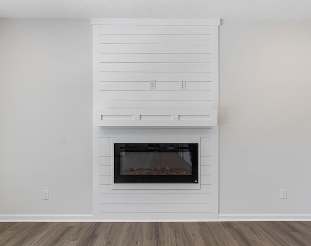 room details with hardwood / wood-style floors and a large fireplace