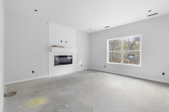 unfurnished living room with concrete flooring and a large fireplace