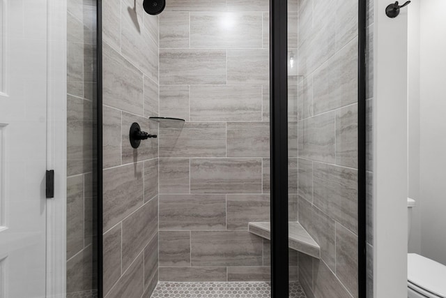 bathroom featuring toilet and a shower with shower door