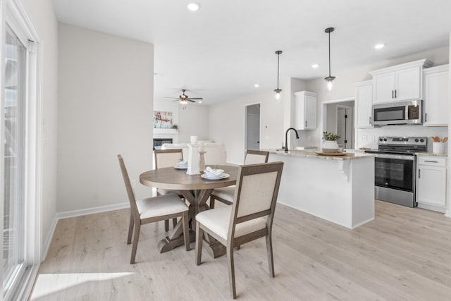 dining room with sink, ceiling fan, and light hardwood / wood-style flooring