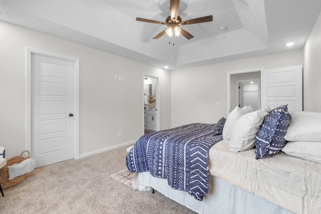 bedroom featuring ceiling fan, connected bathroom, a tray ceiling, and carpet floors