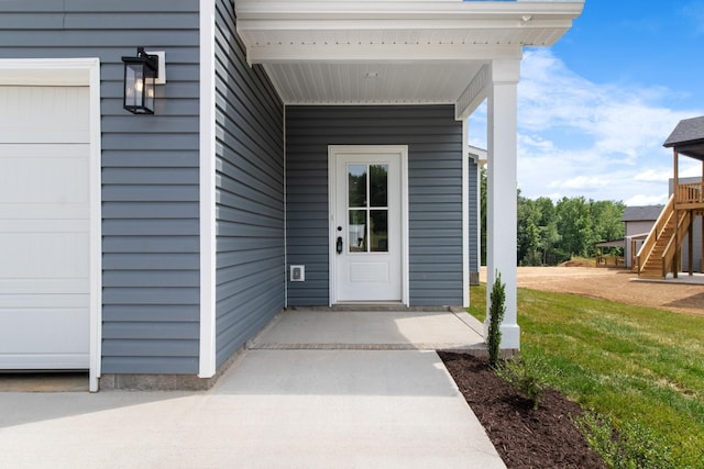 property entrance featuring a garage and a lawn