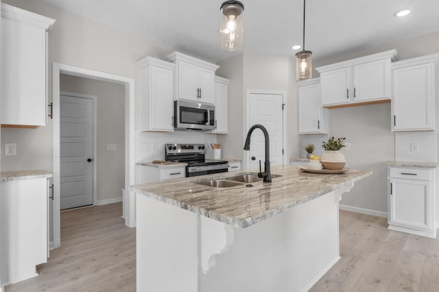 kitchen featuring white cabinetry, appliances with stainless steel finishes, decorative light fixtures, and sink