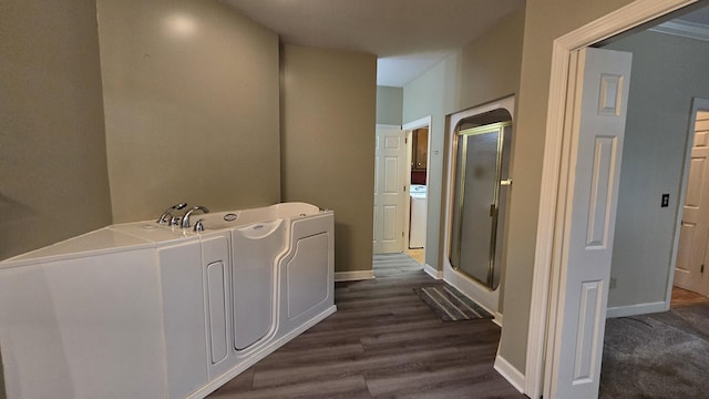 bathroom with plus walk in shower, washer / dryer, and hardwood / wood-style floors