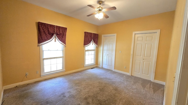 unfurnished bedroom featuring light carpet, two closets, and ceiling fan