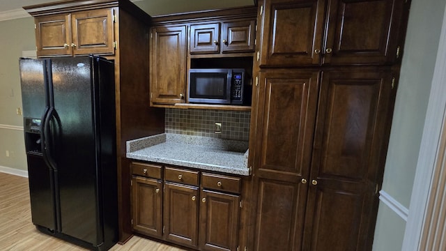 kitchen featuring dark brown cabinetry, tasteful backsplash, crown molding, black refrigerator with ice dispenser, and light hardwood / wood-style floors