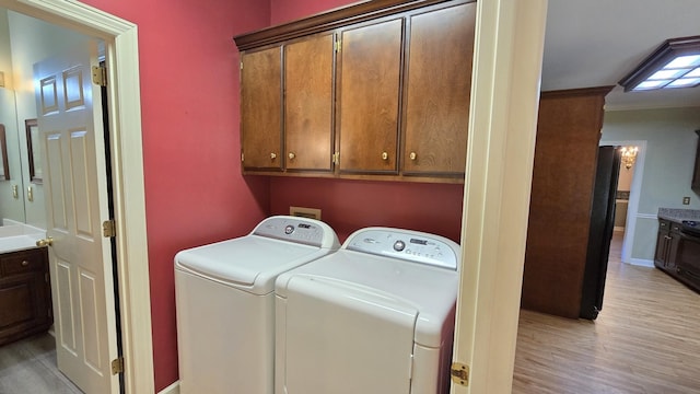 laundry room with cabinets, light hardwood / wood-style floors, and washing machine and dryer