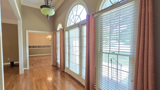 interior space with an inviting chandelier, ornamental molding, and light wood-type flooring