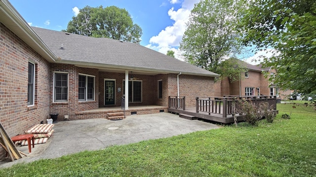 back of house featuring a wooden deck, a lawn, and a patio area