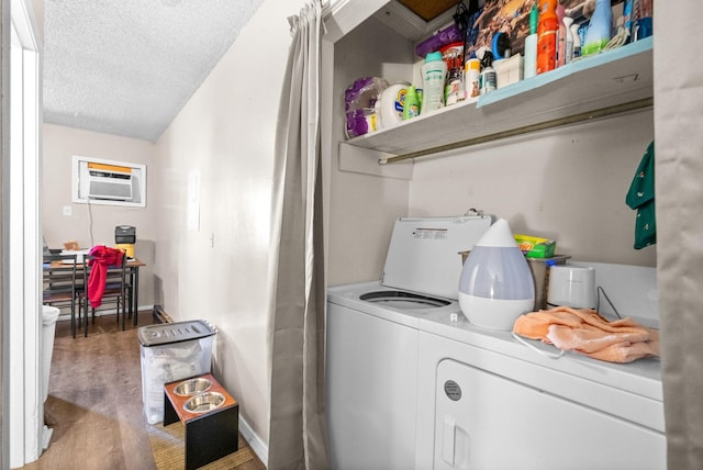 laundry room with a wall mounted air conditioner, washer and clothes dryer, wood-type flooring, and a textured ceiling