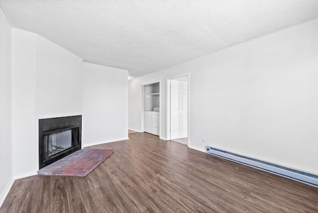 unfurnished living room with dark wood-type flooring, separate washer and dryer, a textured ceiling, baseboard heating, and a fireplace