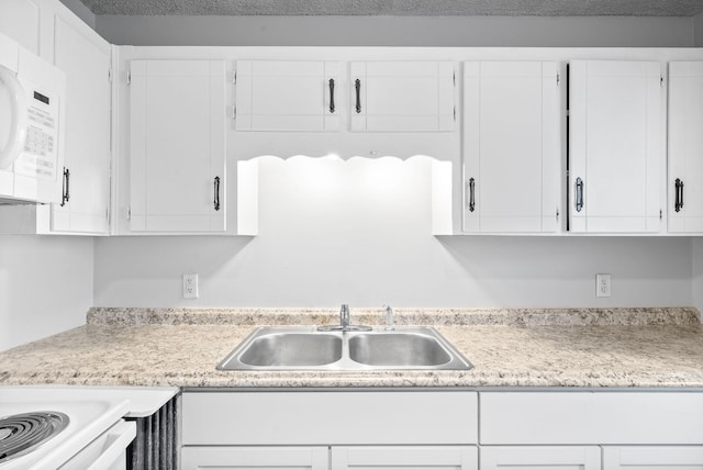 kitchen featuring sink, white cabinets, and a textured ceiling