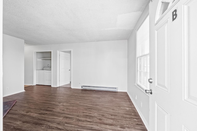 unfurnished room featuring dark wood-type flooring, washer and clothes dryer, a textured ceiling, and baseboard heating