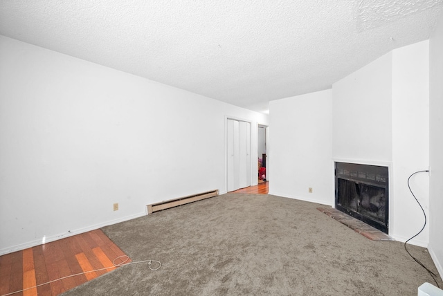 unfurnished living room with a baseboard heating unit, carpet floors, and a textured ceiling