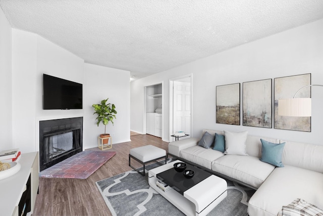 living room featuring hardwood / wood-style flooring, washing machine and dryer, and a textured ceiling