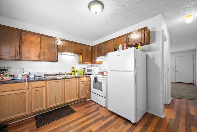 kitchen featuring sink, white appliances, dark wood-type flooring, and a textured ceiling