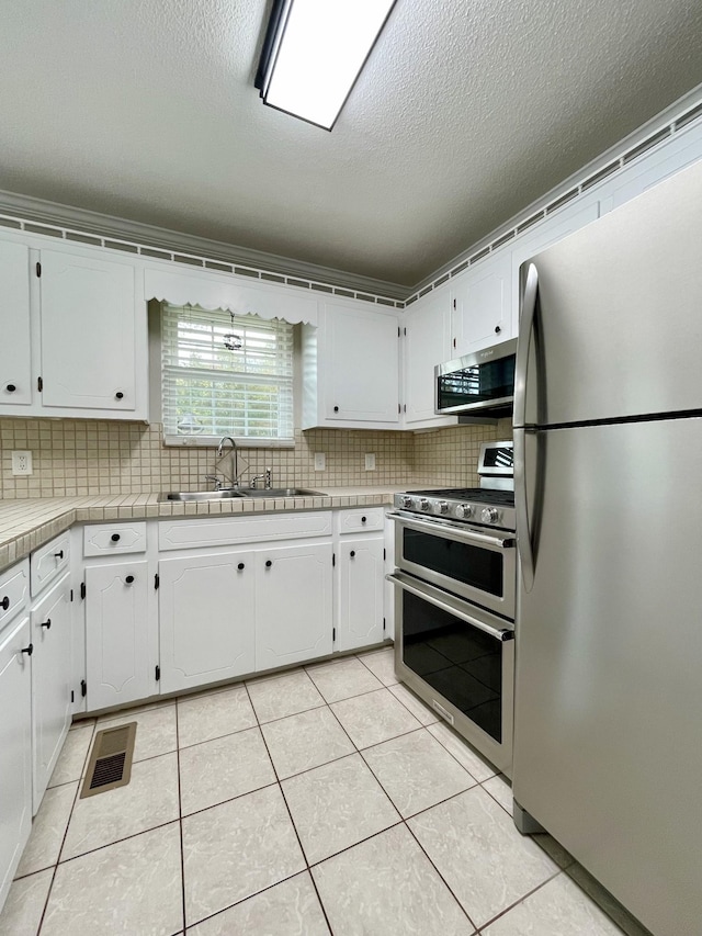 kitchen with white cabinetry, sink, light tile patterned floors, and stainless steel appliances