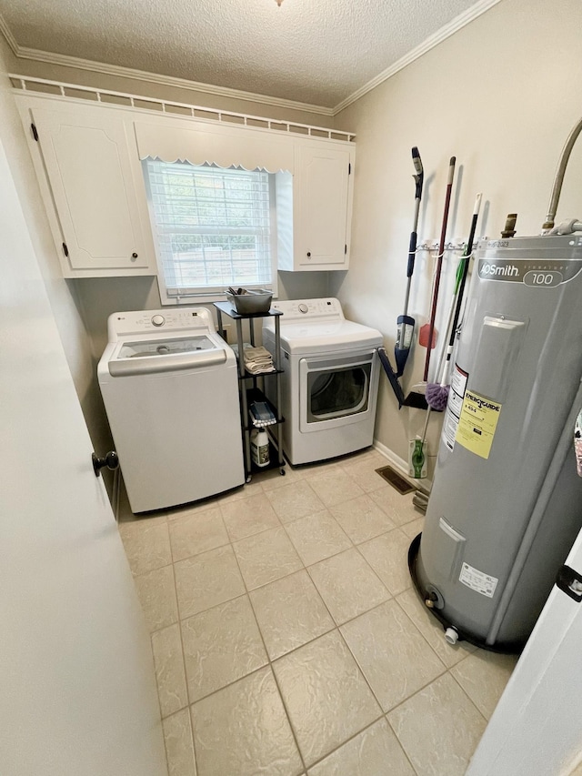 clothes washing area featuring cabinets, washing machine and clothes dryer, crown molding, electric water heater, and a textured ceiling