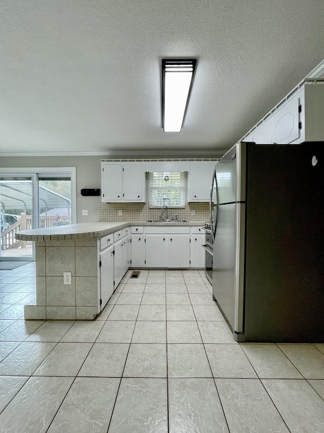 kitchen with stainless steel refrigerator, white cabinetry, and sink