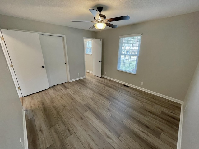 unfurnished bedroom featuring a closet, ceiling fan, a textured ceiling, and light hardwood / wood-style flooring