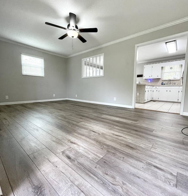 empty room featuring ornamental molding, a textured ceiling, ceiling fan, and light wood-type flooring