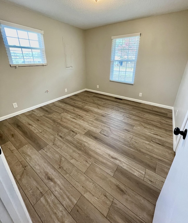 unfurnished room with plenty of natural light, hardwood / wood-style floors, and a textured ceiling