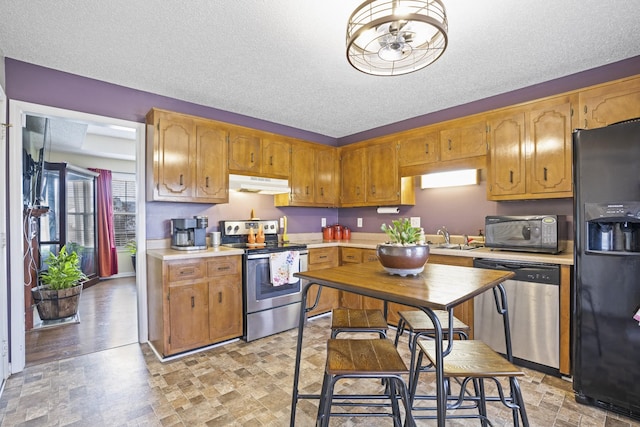 kitchen with sink, a textured ceiling, and black appliances